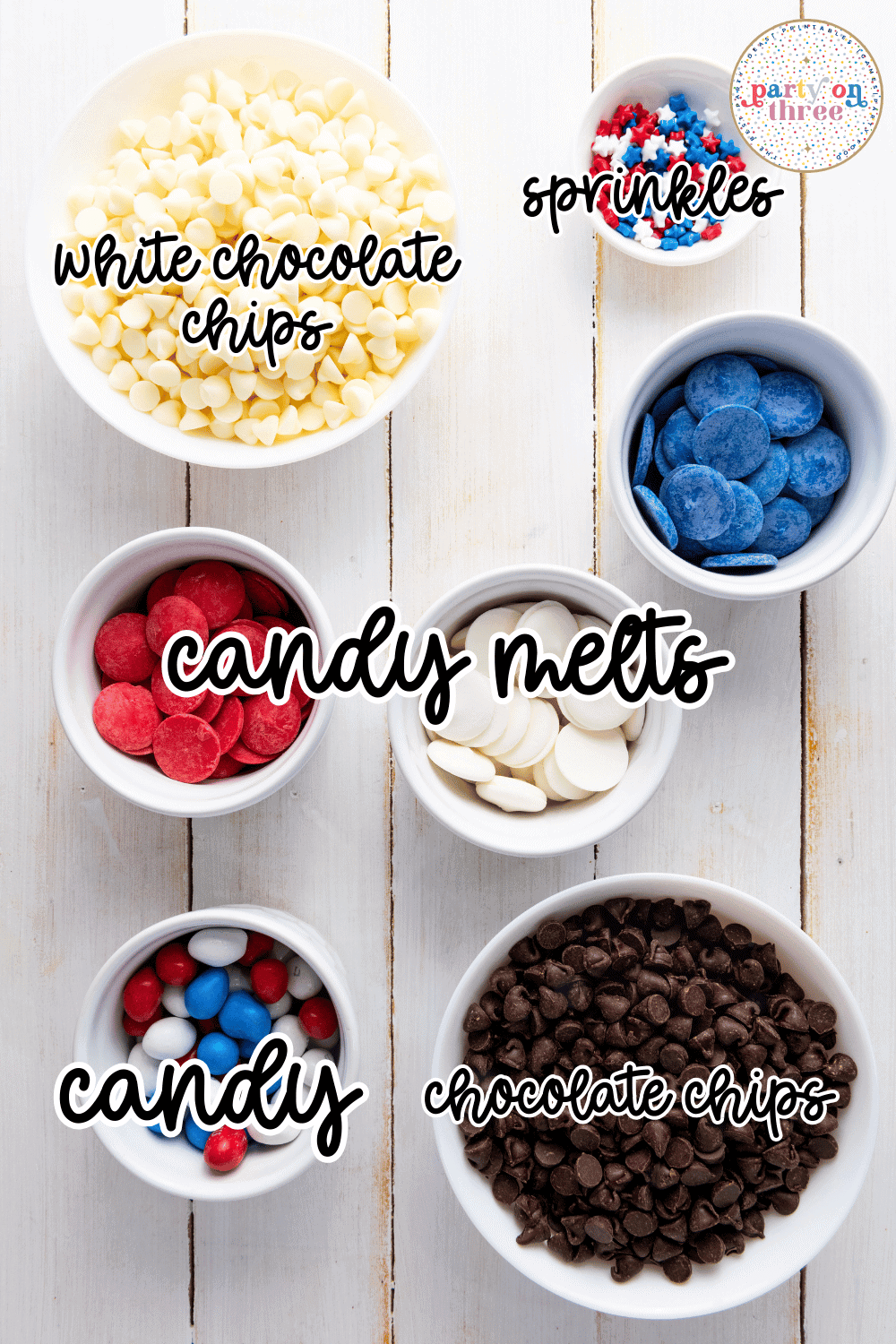Bowls of ingredients for patriotic chocolate bark including white chocolate chips, red and blue candy melts, star sprinkles, M&Ms, and semi-sweet chocolate chips.