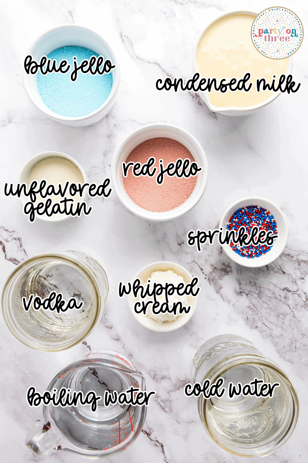 Flat lay of ingredients for 4th of July Jello shots including red and blue Jello powders, unflavored gelatin, condensed milk, vodka, whipped cream, water, and sprinkles.
