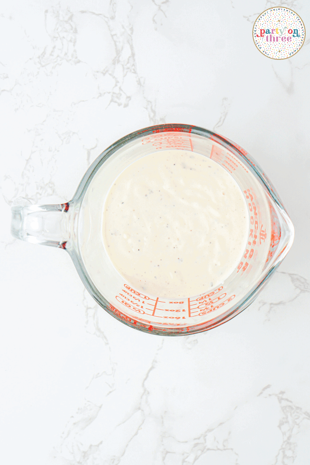 The grinder salad dressing in a glass measuring cup.