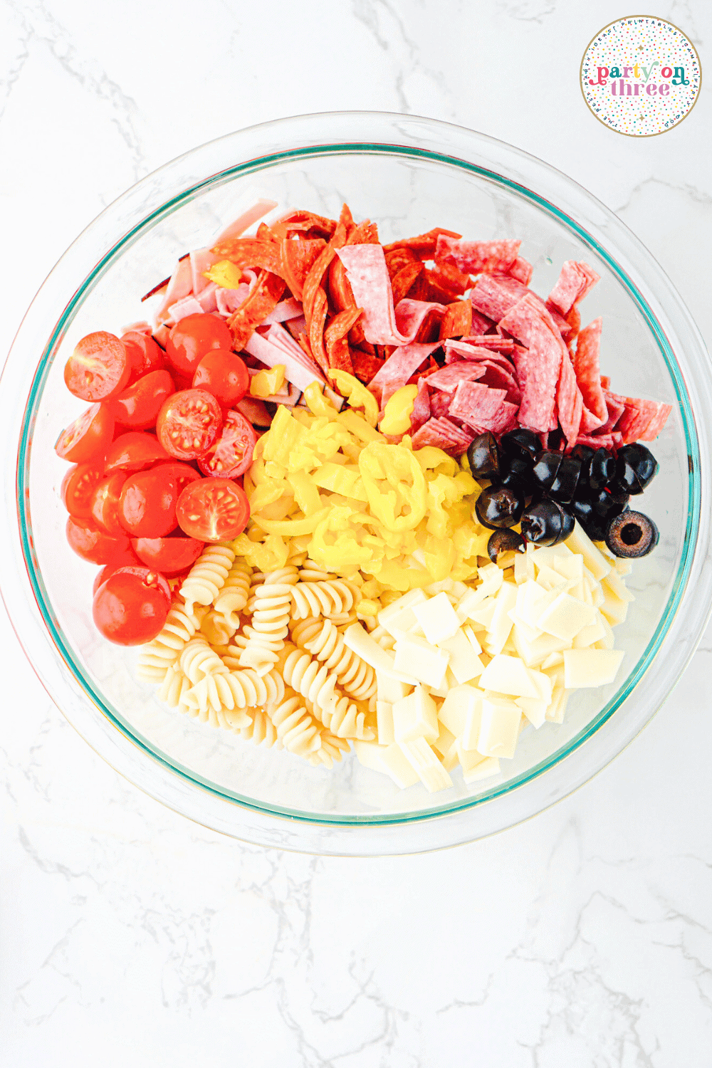All of the meat, cheeses, pasta, and veggies in a mixing bowl.