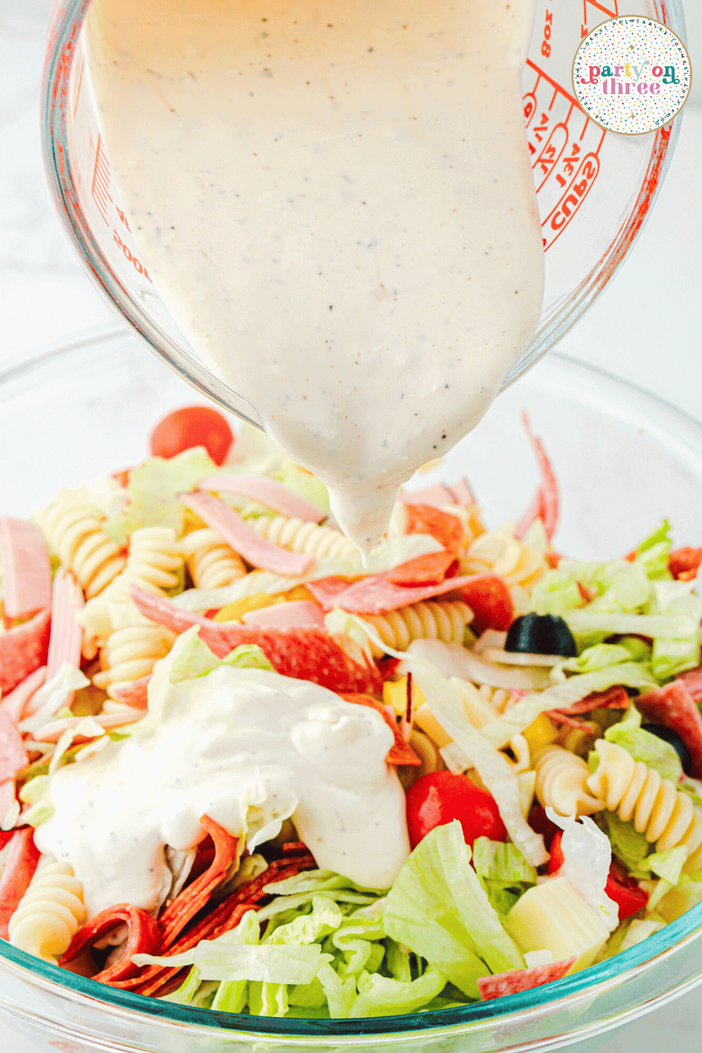 Pouring the dressing over top of the salad.