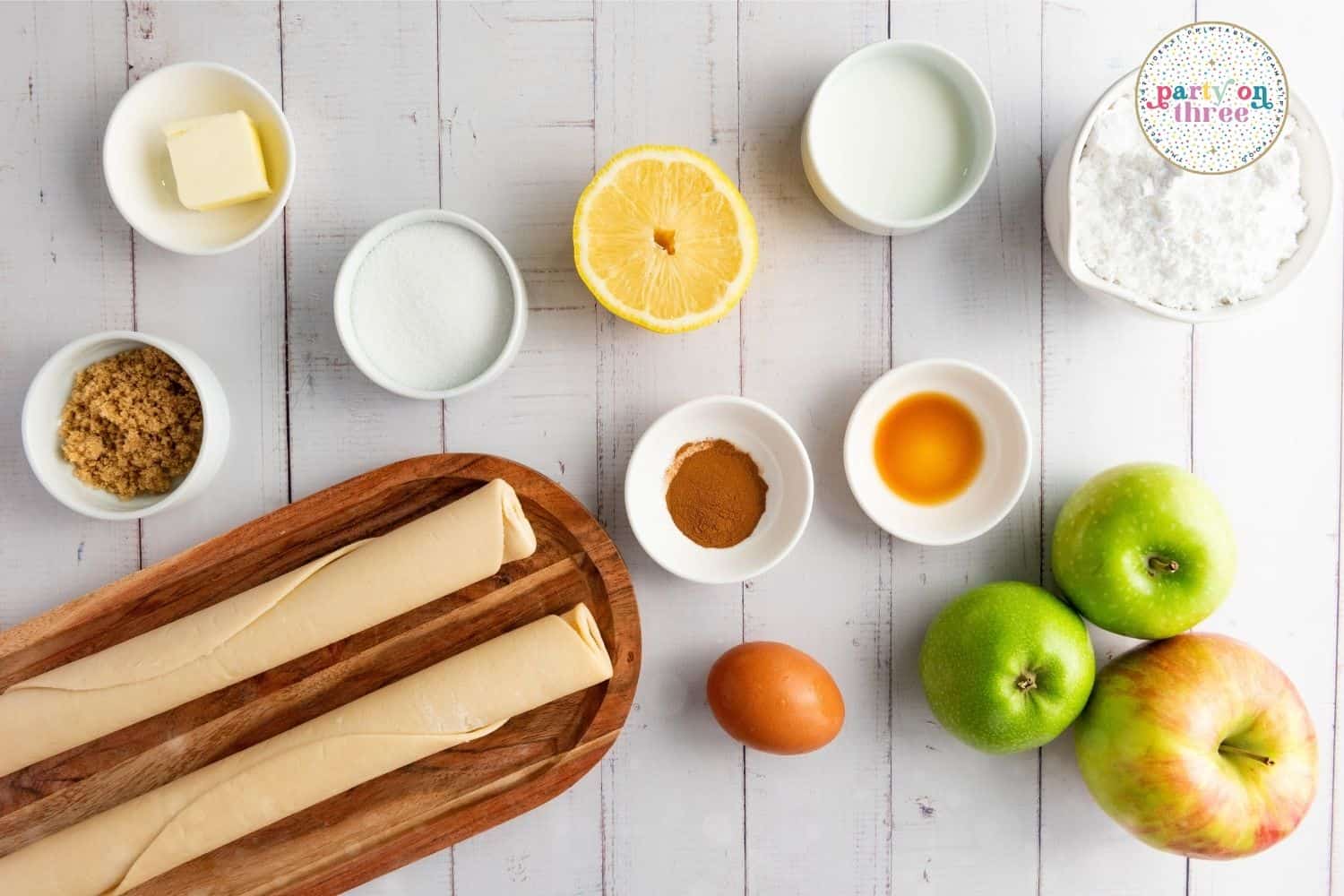 Overhead view of butter, sugar, cinnamon, apples, egg, and pie crust dough for apple hand pies