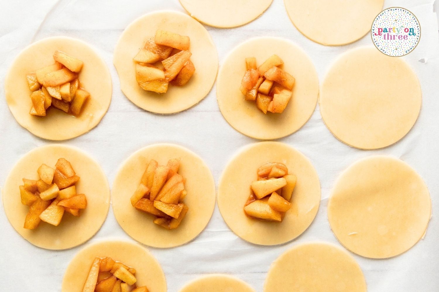 Dough circles topped with spoonfuls of cooked cinnamon apple filling ready to be sealed