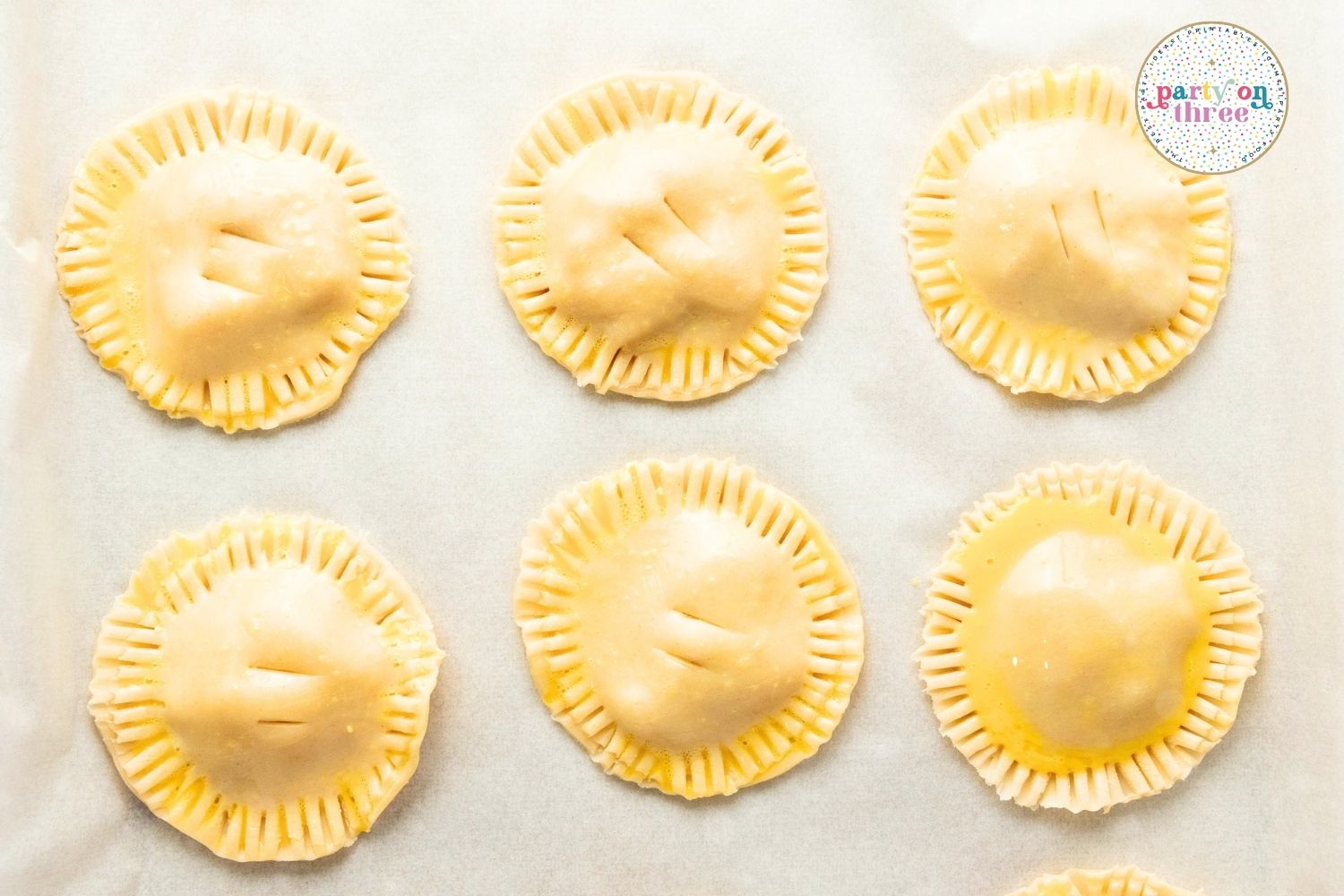 Egg-washed unbaked hand pies with slit vents cut into the tops before baking