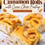 Frosted pumpkin cinnamon rolls on a plate with cream cheese frosting text overlay