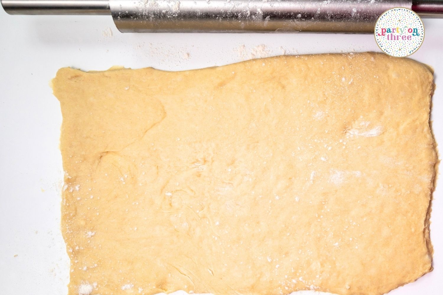 Rolled out rectangle of pumpkin cinnamon roll dough dusted with flour on a counter