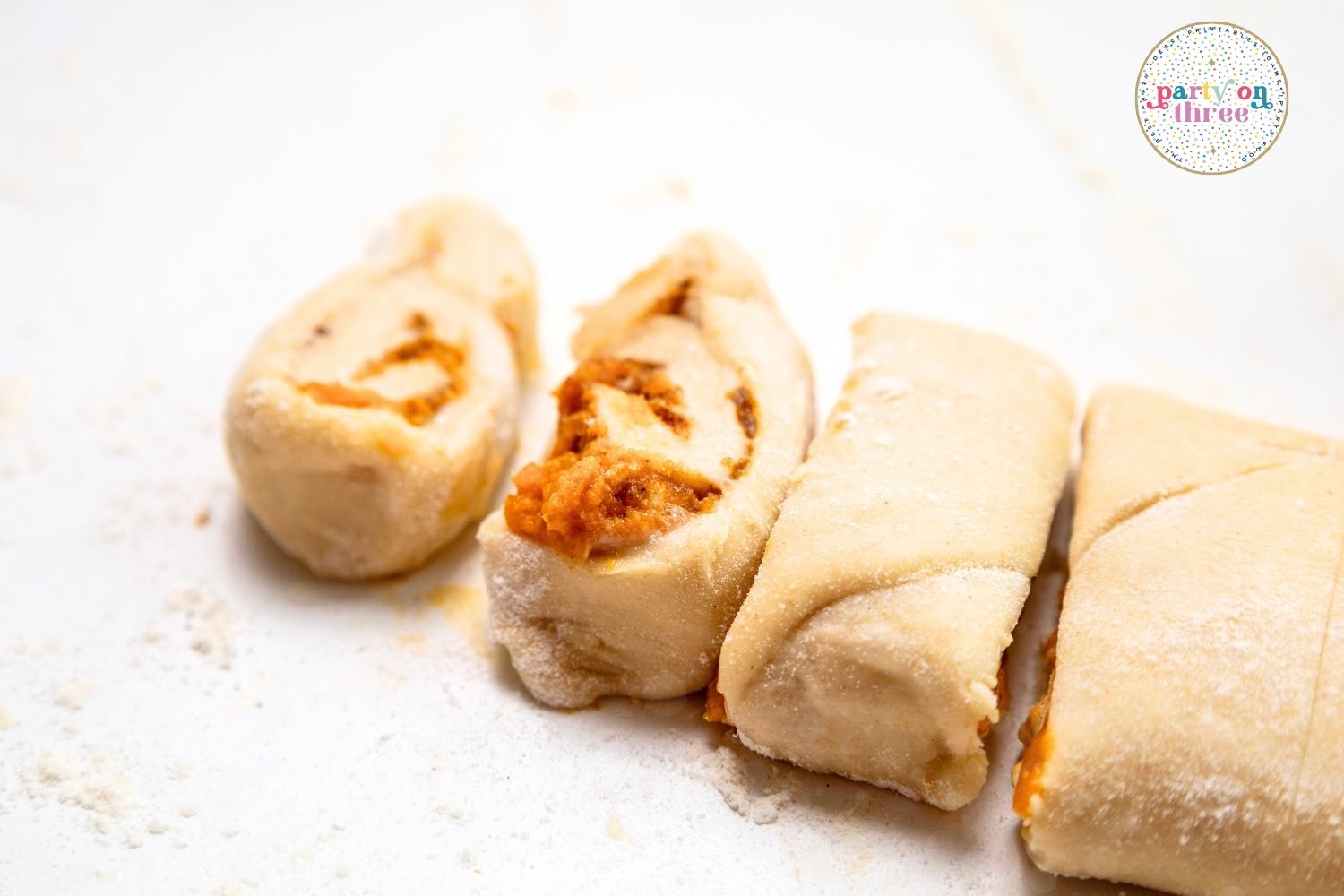 Sliced pumpkin cinnamon roll dough pieces showing swirled pumpkin filling