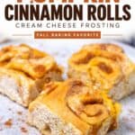 Three pumpkin cinnamon rolls on a speckled plate dusted with cinnamon