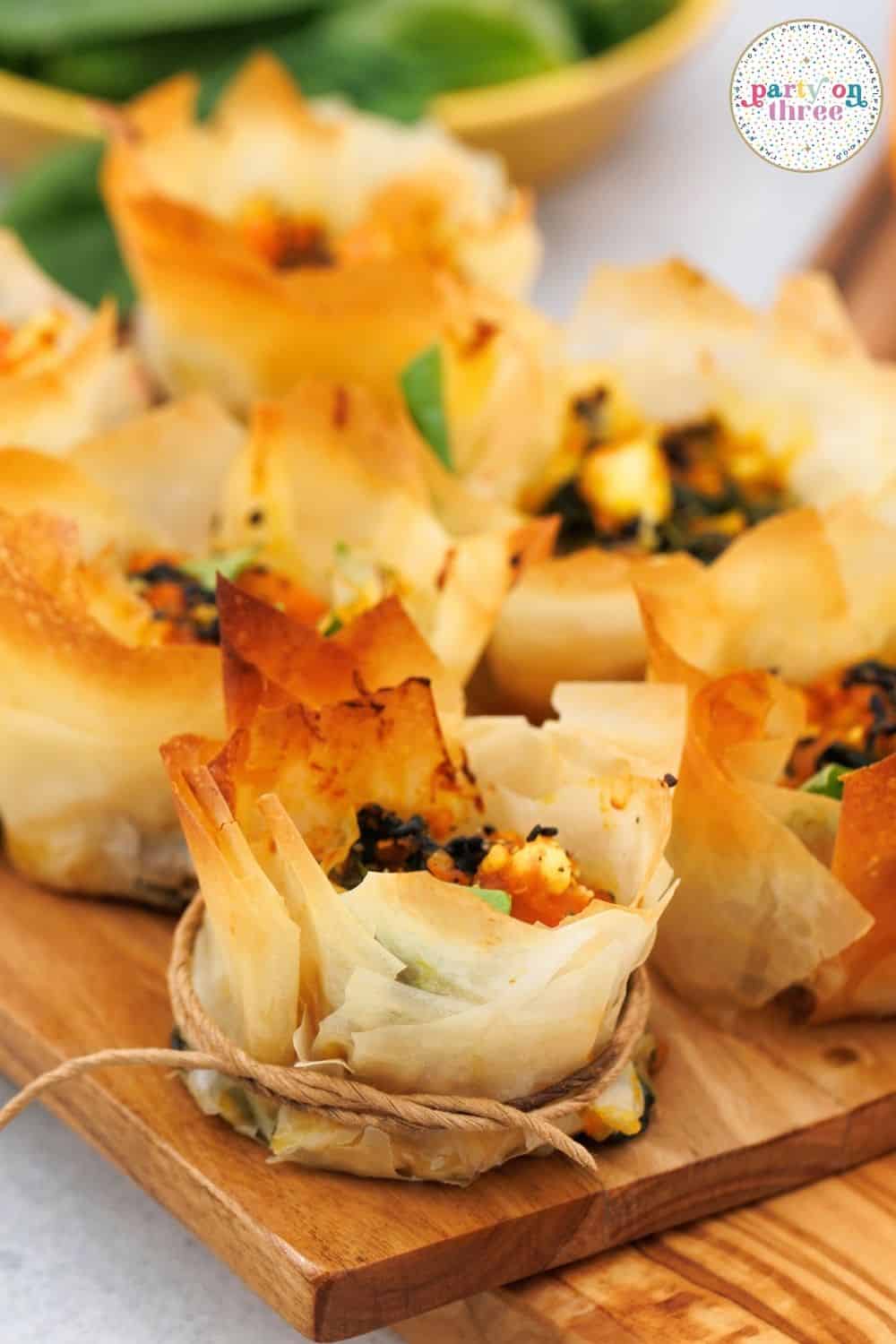 Baked phyllo cups filled with pumpkin, feta, and spinach, twine tied around the base