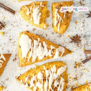 Styled pumpkin scones with vanilla glaze surrounded by mini pumpkins and cinnamon sticks