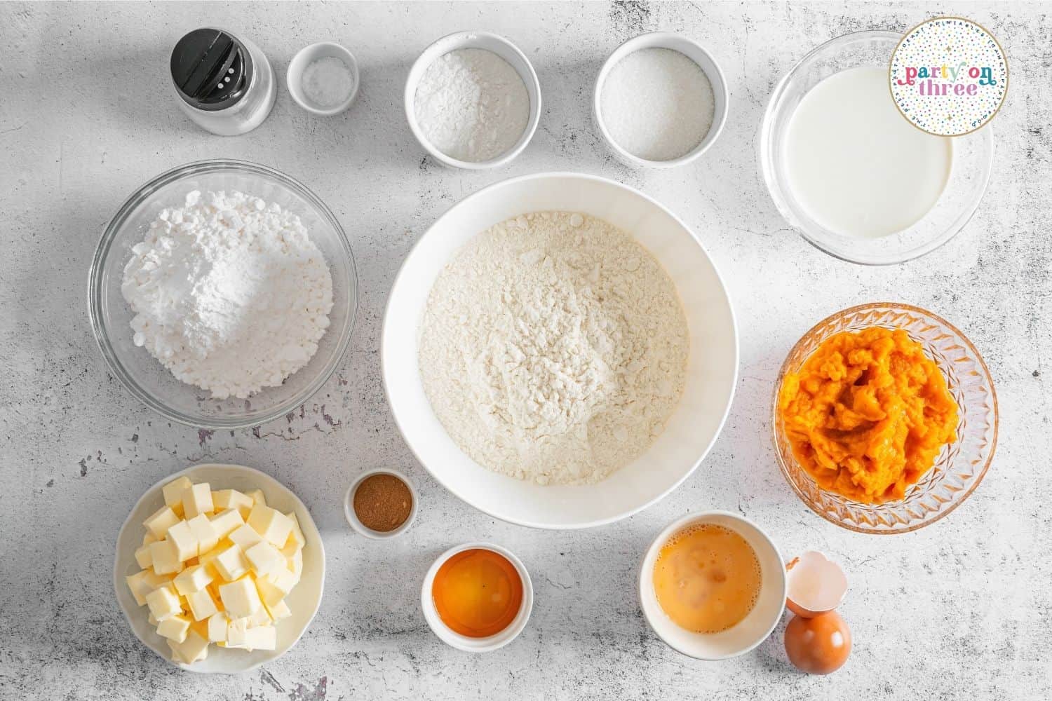 Overhead shot of ingredients for pumpkin scones including flour, butter, pumpkin puree, eggs and cream