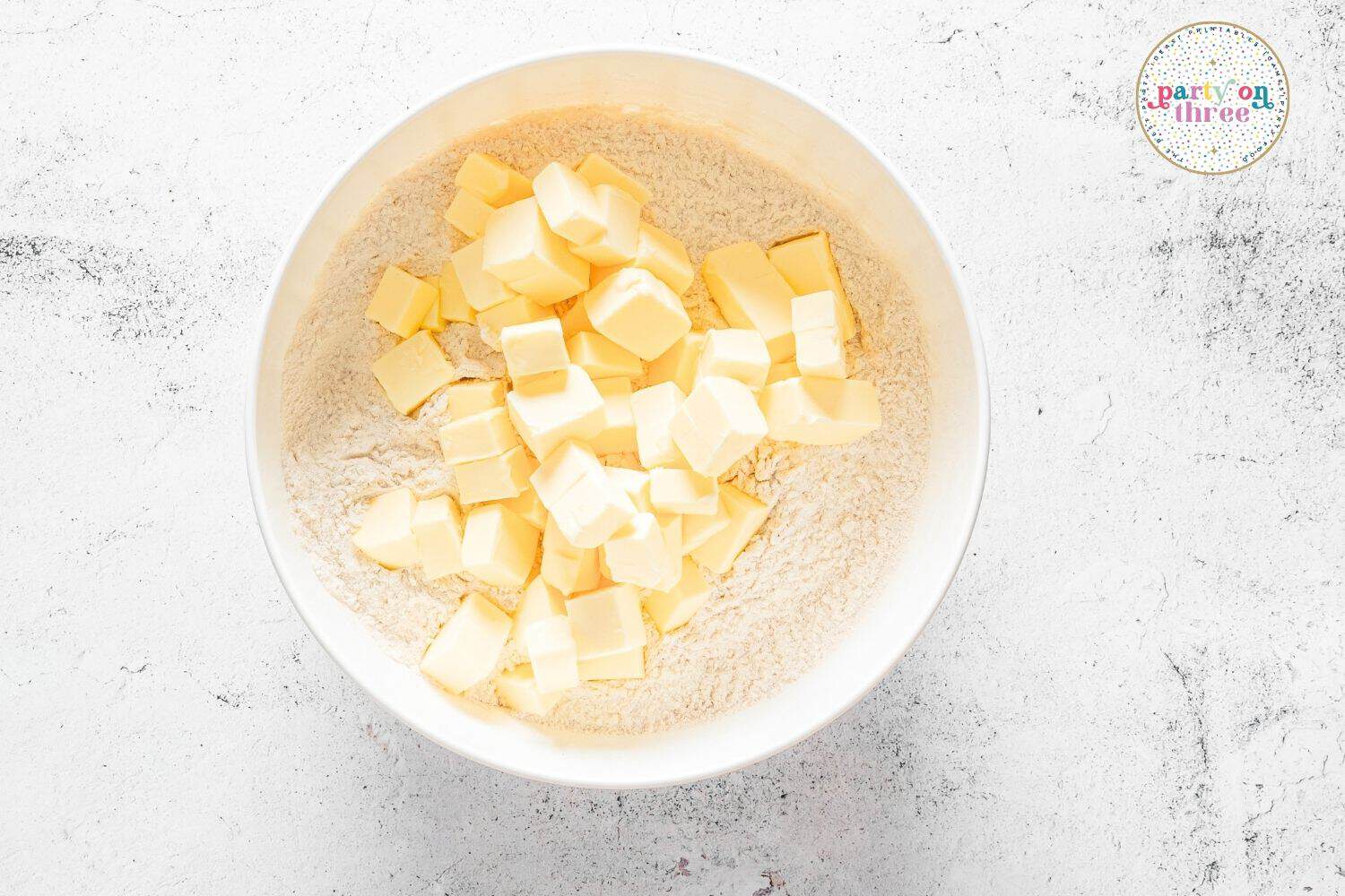 Cubed cold butter added to a bowl of flour mixture for making pumpkin scone dough