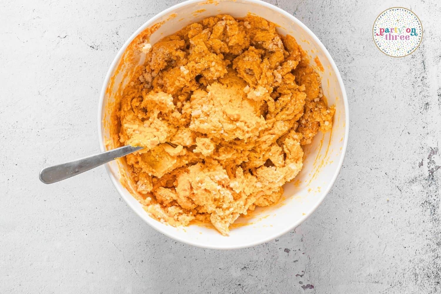 Shaggy pumpkin scone dough coming together in a mixing bowl with a spoon