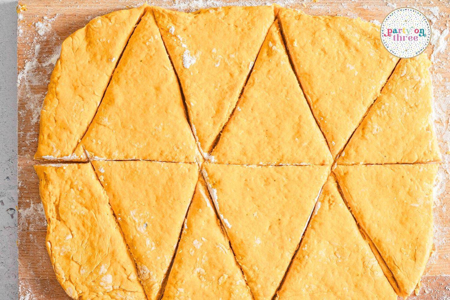 Pumpkin scone dough rolled out and cut into triangle wedges on a floured board