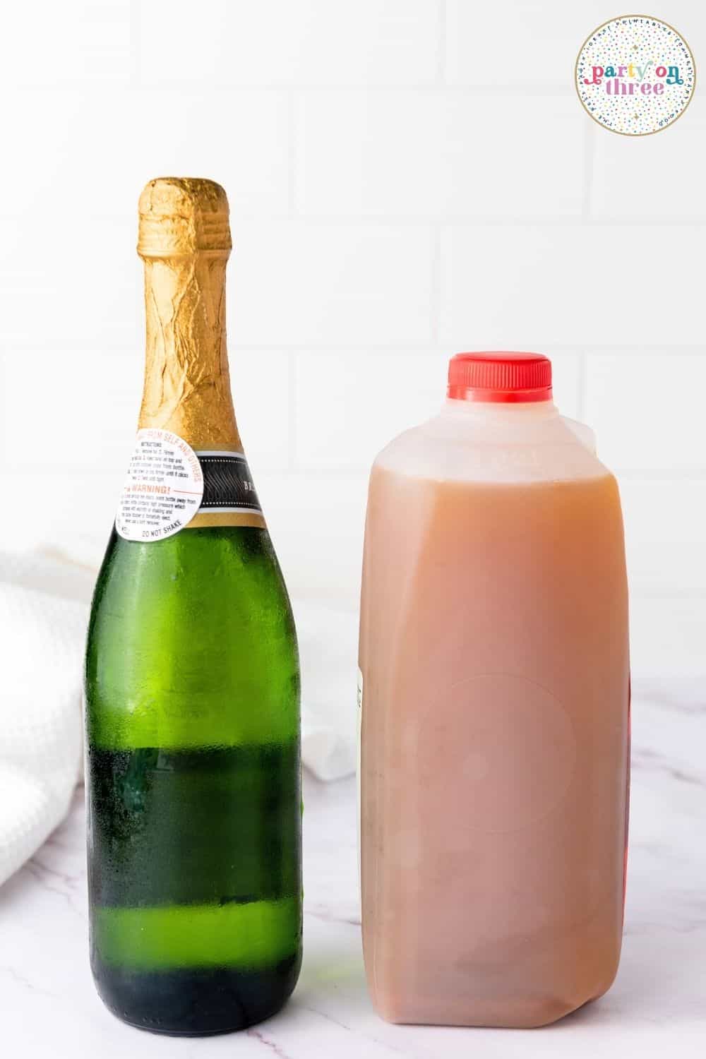 Chilled champagne bottle beside a jug of apple cider, ingredients for Apple Cider Mimosa