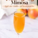 Glass flute of Apple Cider Mimosa on a marble counter with apples blurred in the background