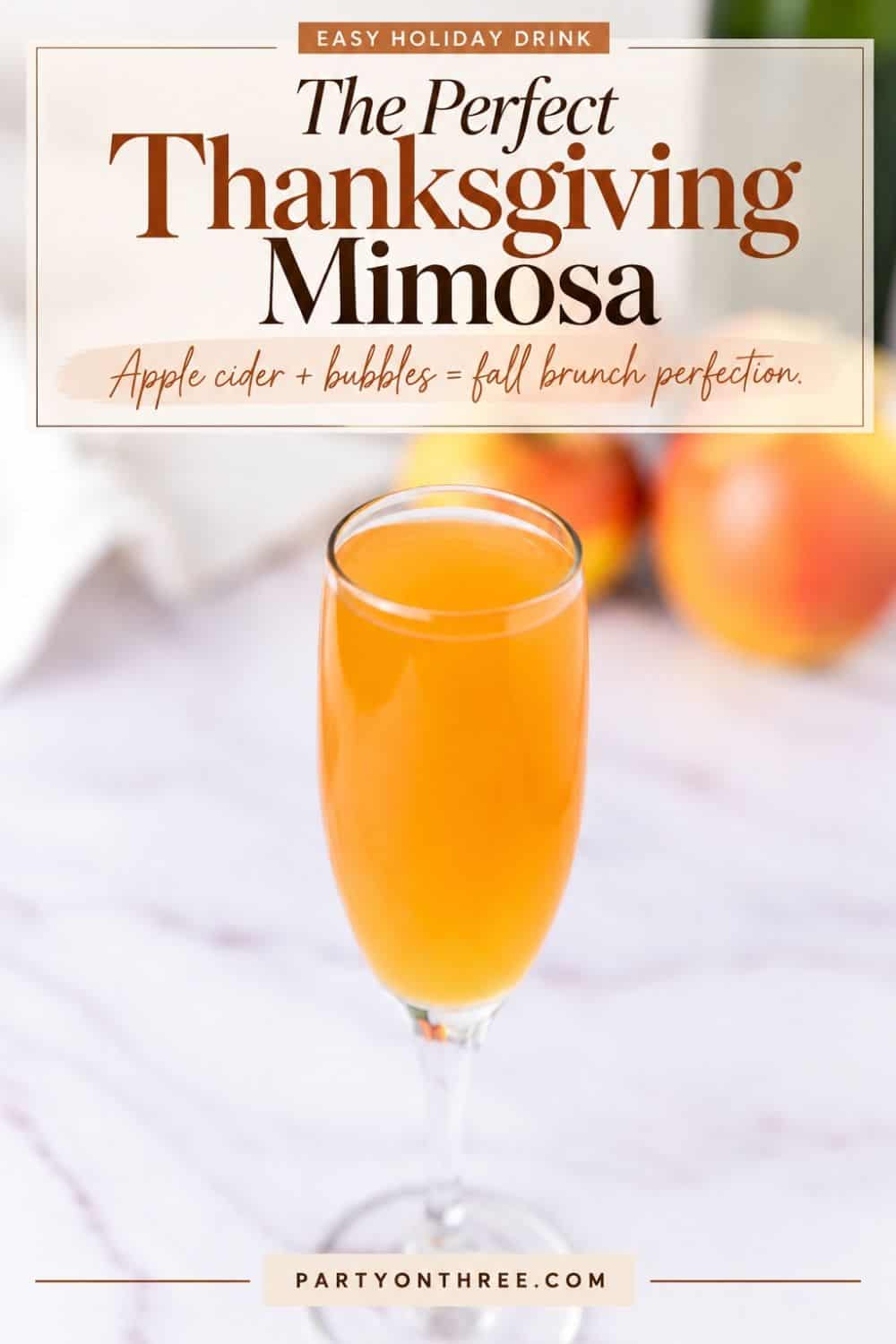 Glass flute of Apple Cider Mimosa on a marble counter with apples blurred in the background