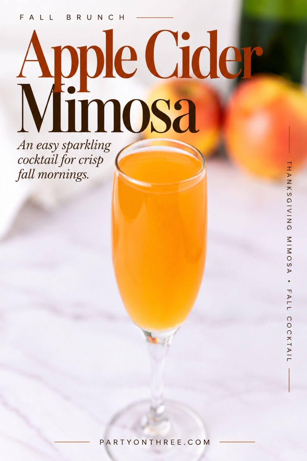Apple Cider Mimosa in a champagne flute on a marble counter with apples in the background