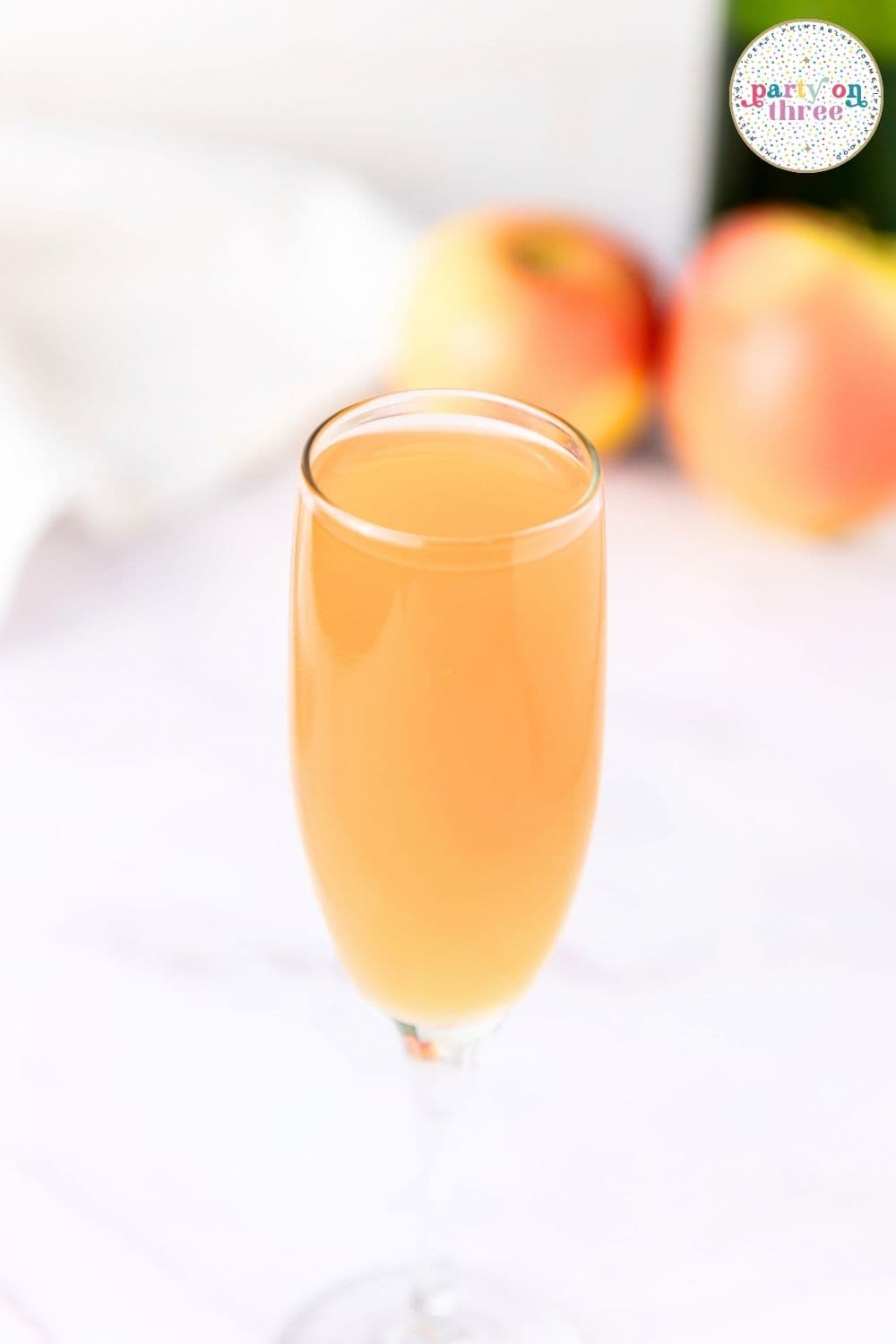 Champagne flute filled with apple cider mimosa, apples blurred in the background