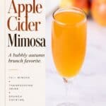 Apple Cider Mimosa in a champagne flute with apples blurred in the background