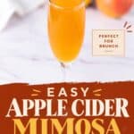 Apple Cider Mimosa in a champagne flute with apples blurred in the background