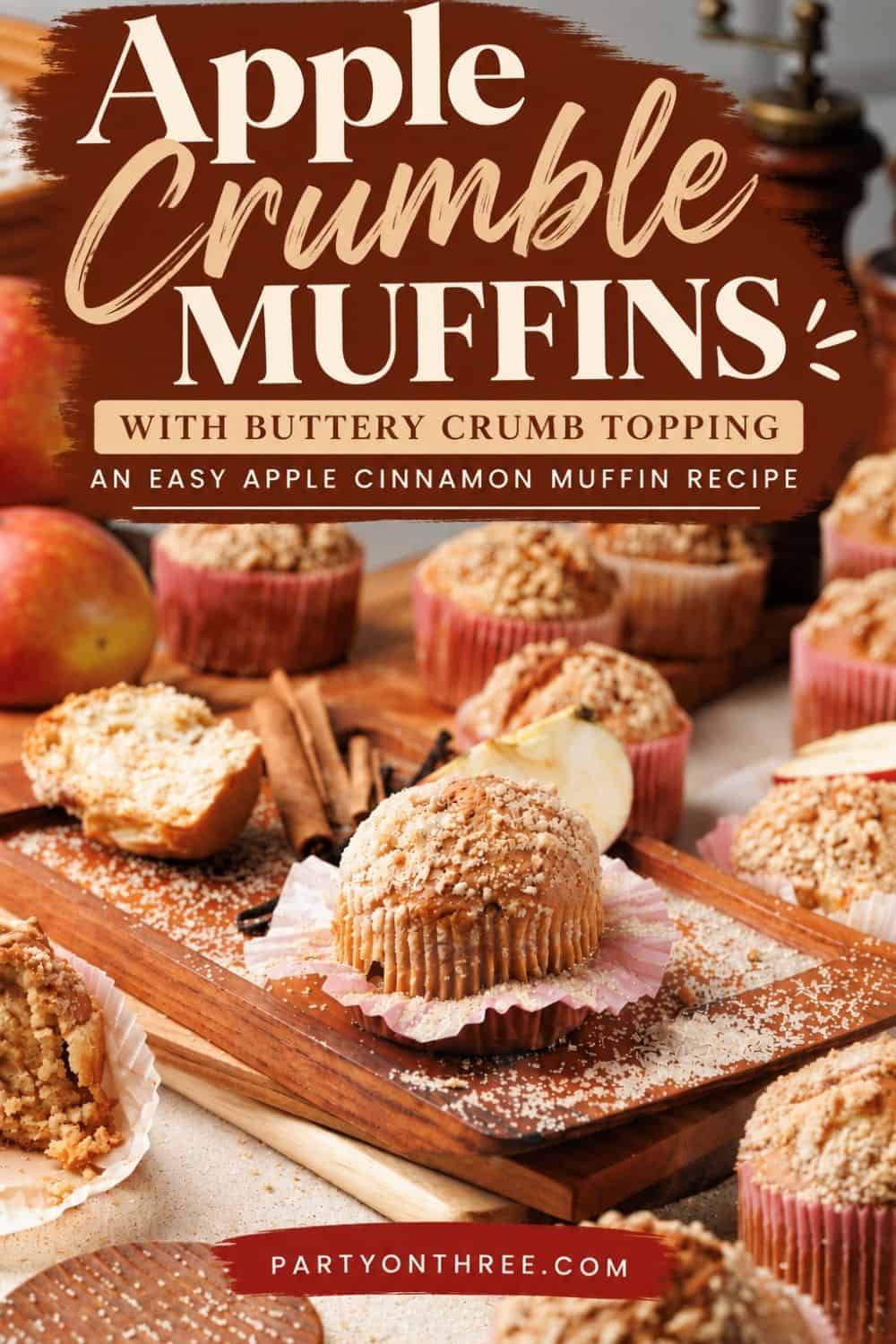 Apple cinnamon muffins with buttery crumble topping on a wooden board, surrounded by apples and cinnamon sticks