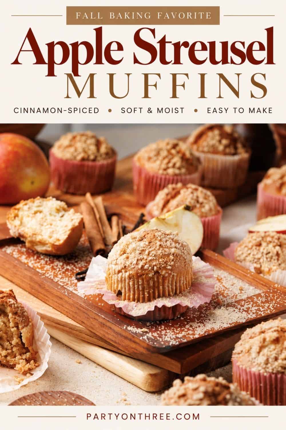 Apple cinnamon muffins with crumble topping on a wood board, surrounded by cinnamon sticks and apple slices