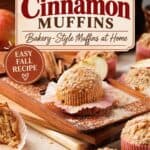 Apple cinnamon muffins topped with crumble on a wooden board, surrounded by cinnamon sticks and apple slices