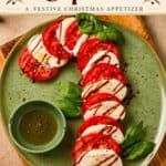 Caprese Candy Cane appetizer on a green plate with tomato, mozzarella, basil, and balsamic drizzle