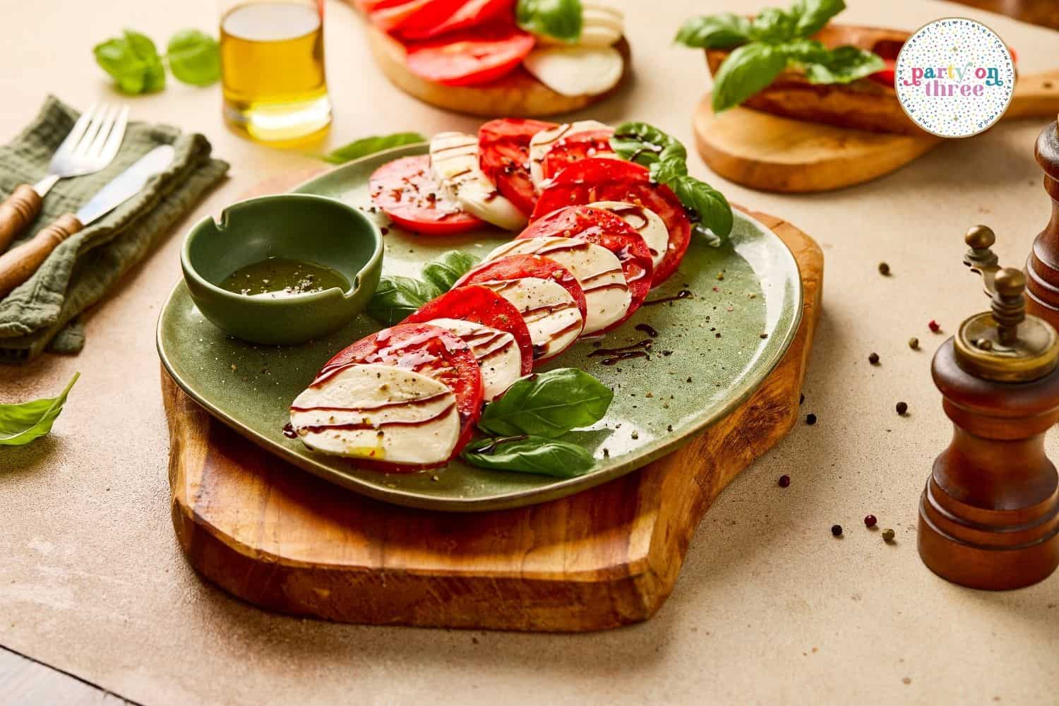 Overlapping tomato and mozzarella slices curved into a candy cane shape on a green plate with balsamic drizzle