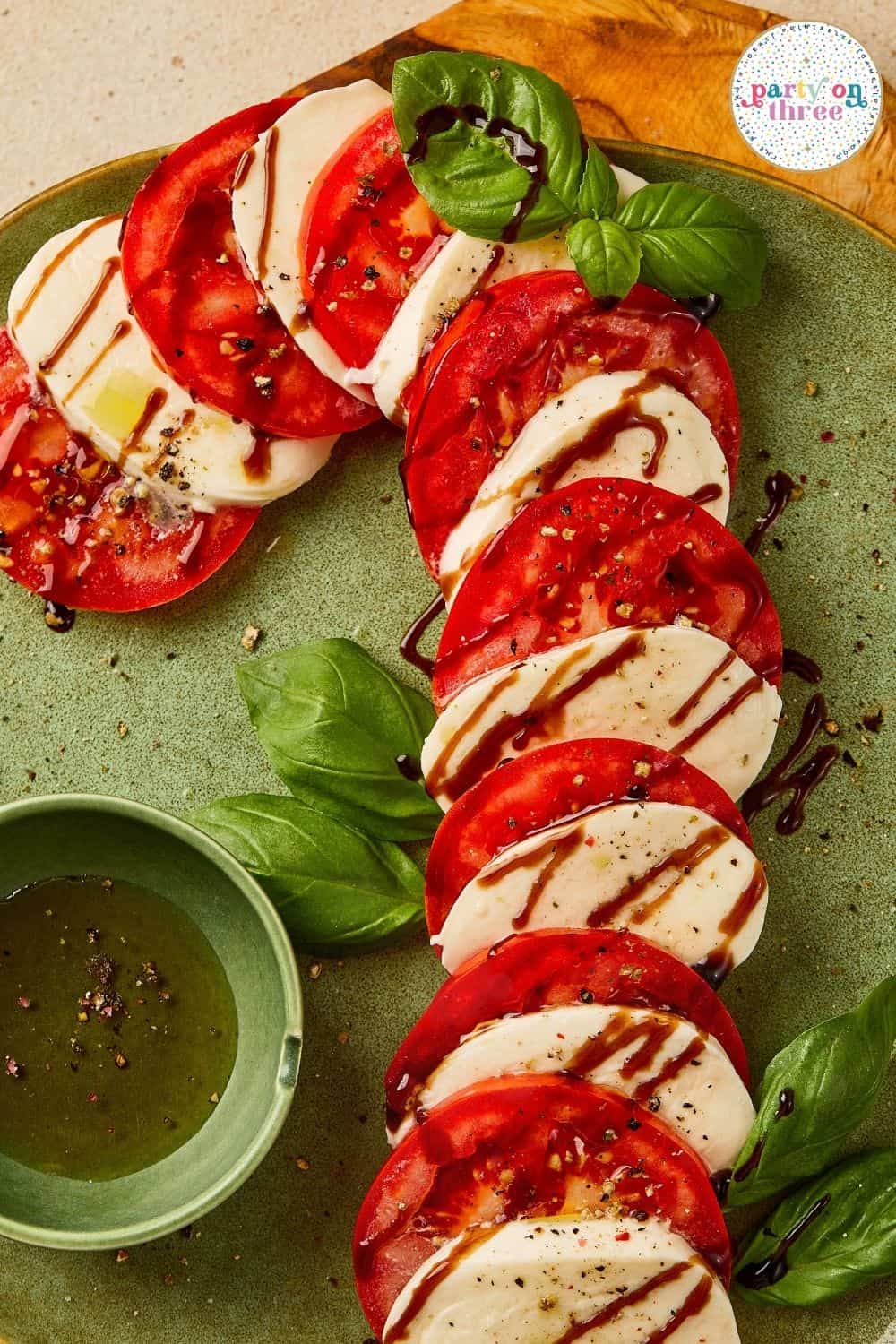 Tomato and mozzarella slices curved into a candy cane shape, drizzled with balsamic glaze and olive oil