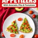 Pita triangles topped with mashed avocado and diced tomatoes shaped like Christmas trees on a white plate