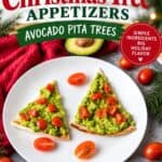 Avocado pita Christmas tree appetizers topped with diced tomatoes, served on a white plate with cherry tomatoes