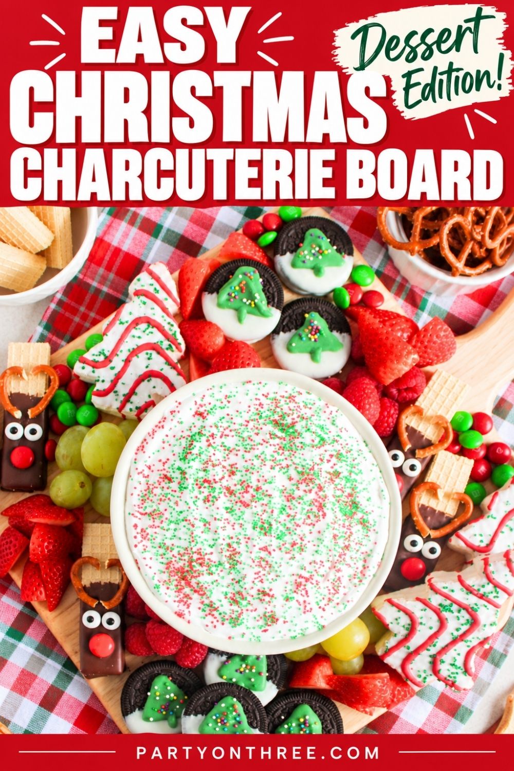 Christmas charcuterie board with marshmallow dip, reindeer pretzels, Oreo trees, strawberries, grapes, and pretzels.