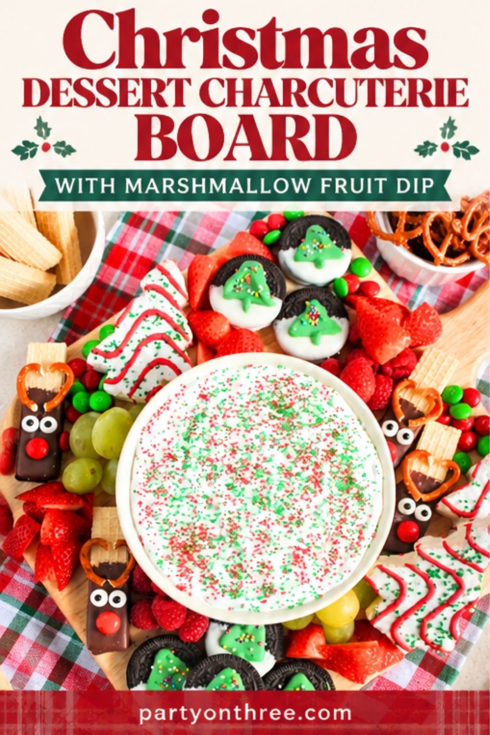 Christmas charcuterie board with marshmallow fruit dip, reindeer pretzels, cookies, and fresh fruit