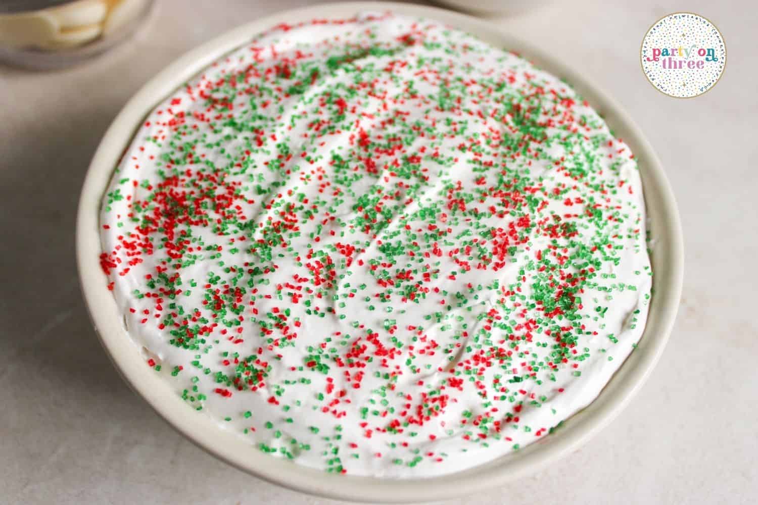 Marshmallow fruit dip topped with red and green holiday sprinkles in a round bowl
