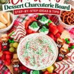 Overhead view of a Christmas charcuterie board with marshmallow fruit dip, reindeer pretzels, and cookies.