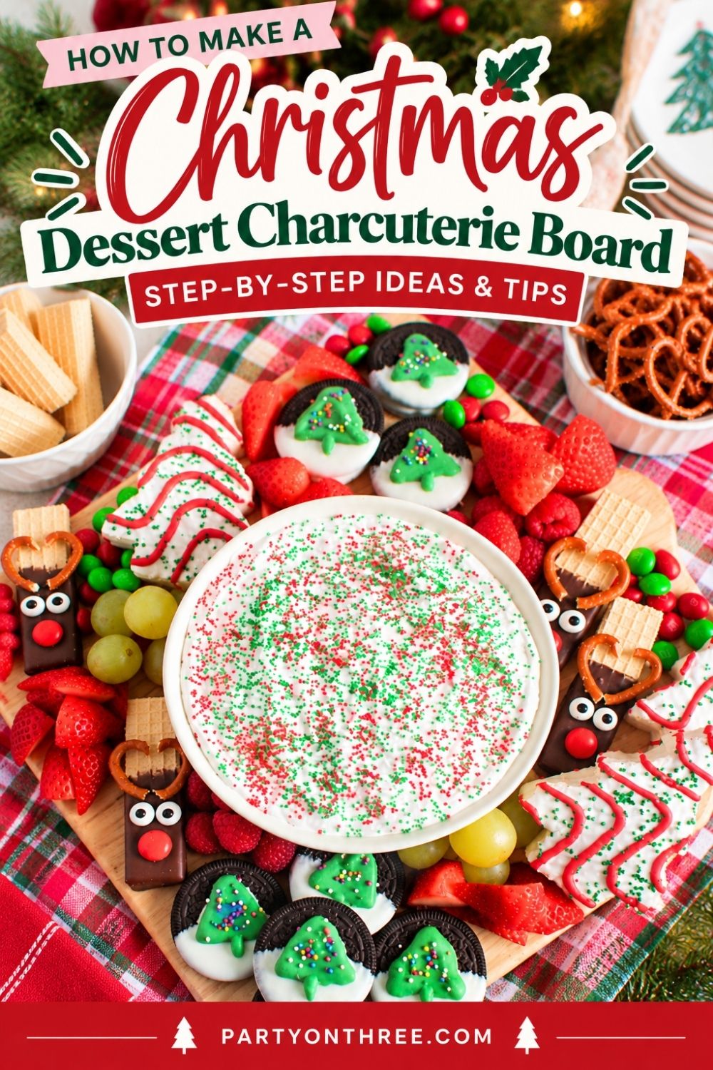 Overhead view of a Christmas charcuterie board with marshmallow fruit dip, reindeer pretzels, and cookies.