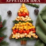 Christmas cheese board shaped like a tree with cheddar cubes, cherry tomatoes, and rosemary sprigs