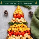 Christmas cheese board shaped like a tree, with cheddar cubes, cherry tomatoes, and rosemary sprigs