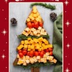 Christmas cheese board shaped like a tree with cheddar cubes, cherry tomatoes, and rosemary sprigs