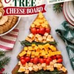Christmas cheese board shaped like a tree, with cheddar cubes, cherry tomatoes, and rosemary sprigs.