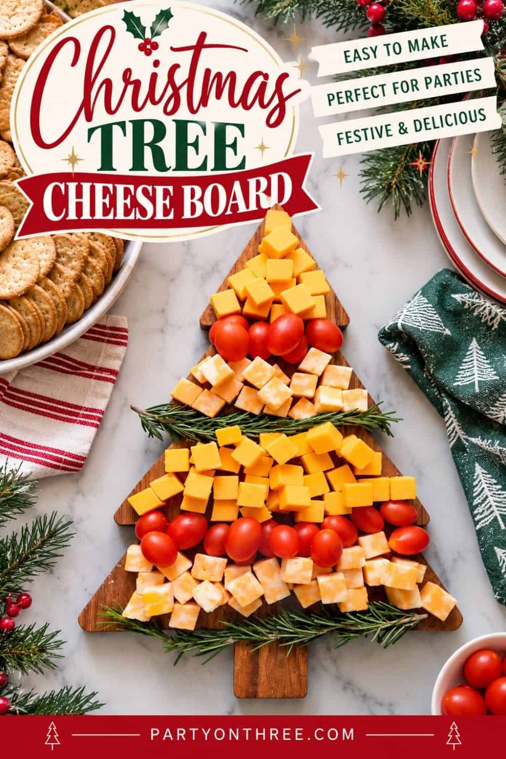 Christmas cheese board shaped like a tree, with cheddar cubes, cherry tomatoes, and rosemary sprigs.
