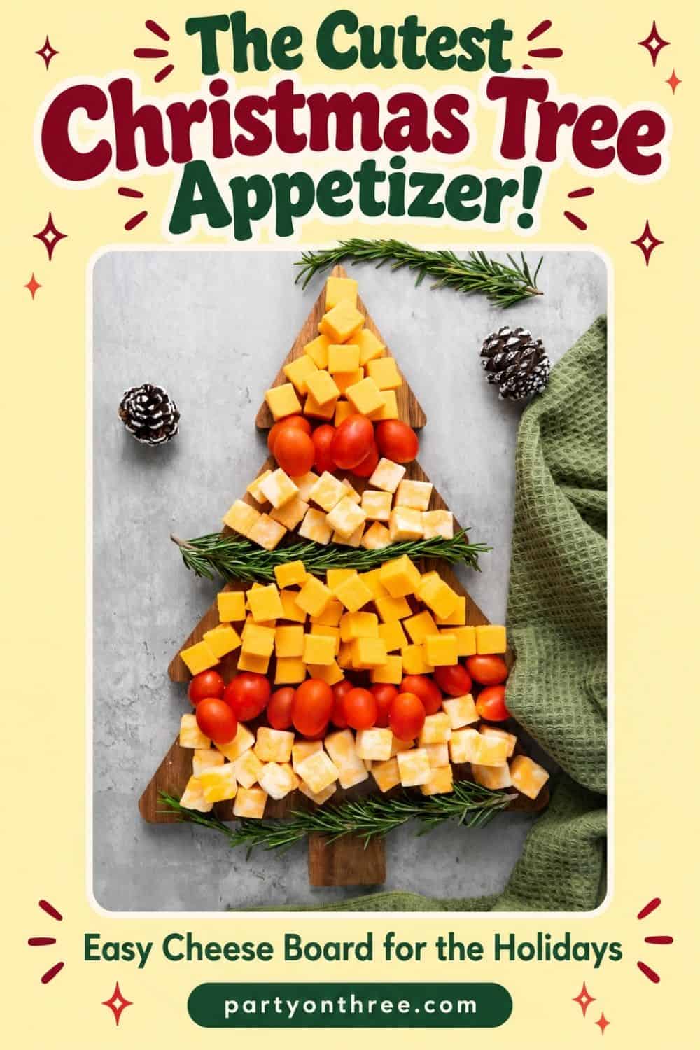 Christmas tree shaped cheese board with cheddar cubes, cherry tomatoes, and rosemary sprigs on a wooden board