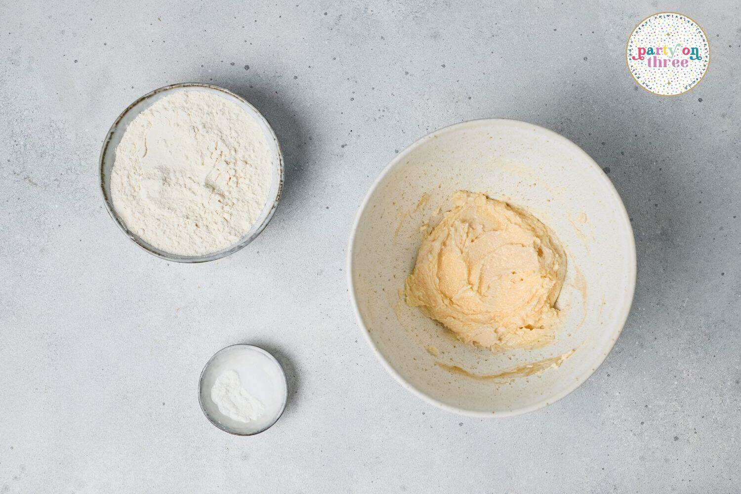 Creamed butter and sugar mixture in a bowl with flour and salt measured separately for cookie dough