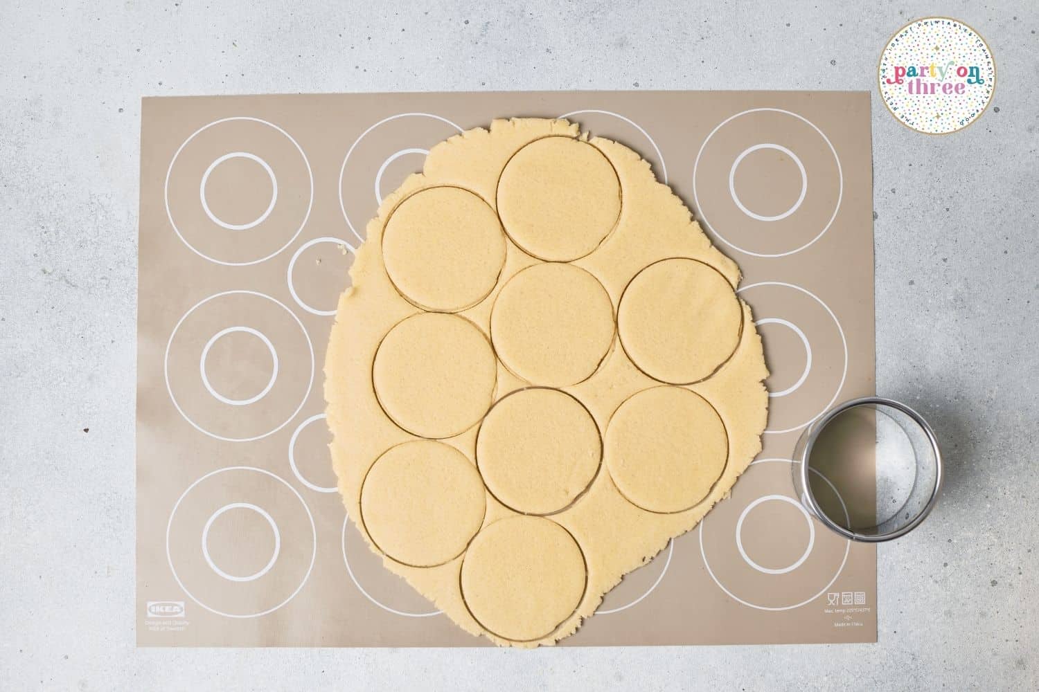 Sugar cookie dough rolled out and cut into circles with a round cutter on a silicone baking mat
