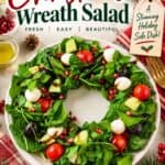 Christmas Wreath Salad shaped on a plate with greens, mozzarella, tomatoes, olives, pomegranate seeds and balsamic glaze