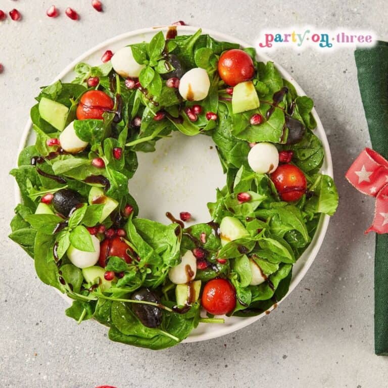 Christmas Wreath Salad with mozzarella, tomatoes, pomegranate seeds and balsamic drizzle on a round plate