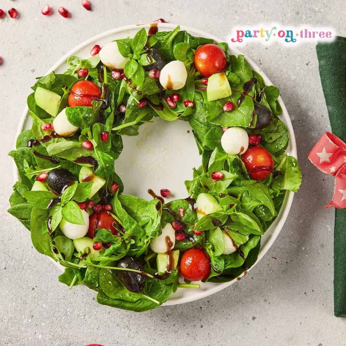 Christmas Wreath Salad with mozzarella, tomatoes, pomegranate seeds and balsamic drizzle on a round plate