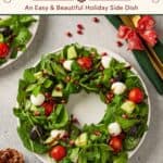 Christmas Wreath Salad shaped on a plate with greens, mozzarella, tomatoes, olives, pomegranate seeds and balsamic drizzle.